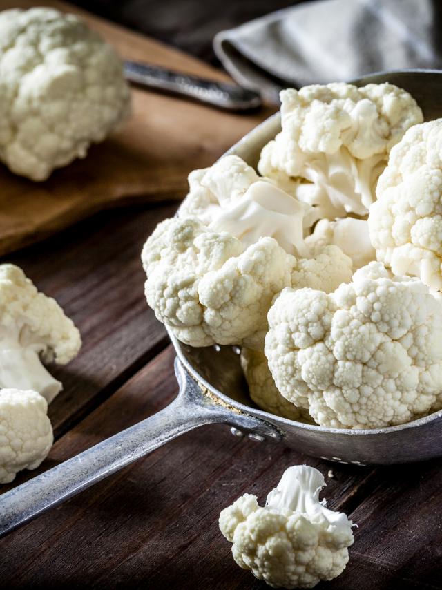 Fresh organic cauliflower in an old metal colander shot on rustic wooden table. This vegetable is considered a healthy salad ingredient. Predominant colors are white and brown. Low key DSRL studio photo taken with Canon EOS 5D Mk II and Canon EF 100mm f/2.8L Macro IS USM